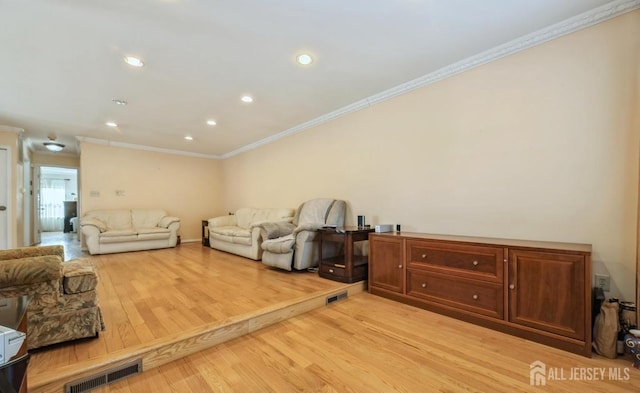 living room with ornamental molding, light wood-type flooring, and recessed lighting