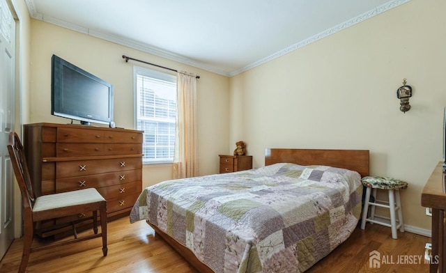 bedroom featuring ornamental molding, wood finished floors, and baseboards
