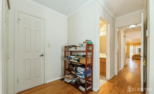hallway with ornamental molding, light wood-type flooring, and baseboards