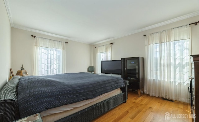 bedroom featuring wood finished floors and crown molding