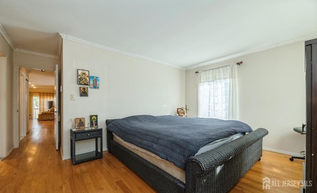 bedroom featuring multiple windows, wood finished floors, baseboards, and ornamental molding