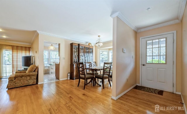 doorway to outside featuring crown molding, a chandelier, light wood-type flooring, and baseboards