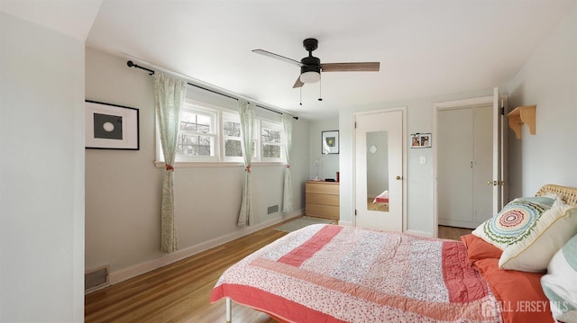 bedroom with visible vents, baseboards, wood finished floors, and ceiling fan