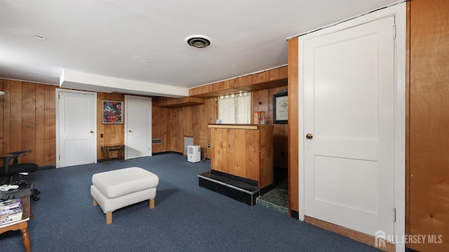 sitting room featuring wooden walls and carpet floors