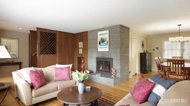 living room featuring a fireplace, light wood-style flooring, baseboards, and a notable chandelier
