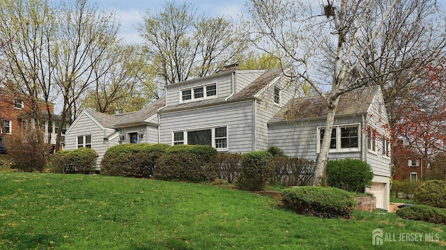 view of home's exterior featuring a chimney, an attached garage, and a yard