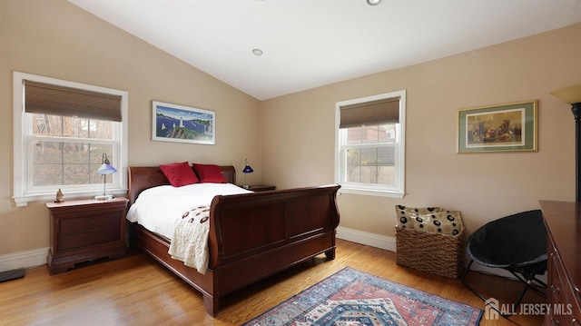bedroom featuring lofted ceiling, baseboards, light wood finished floors, and multiple windows