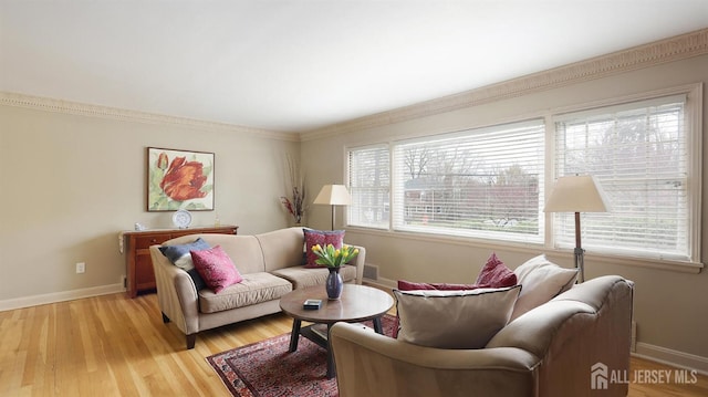 living room with crown molding, light wood-style flooring, and baseboards
