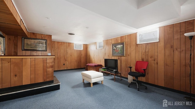 living area featuring carpet and wood walls