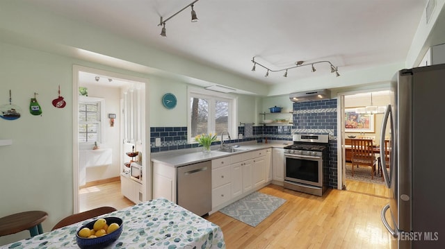 kitchen featuring track lighting, under cabinet range hood, a sink, and appliances with stainless steel finishes