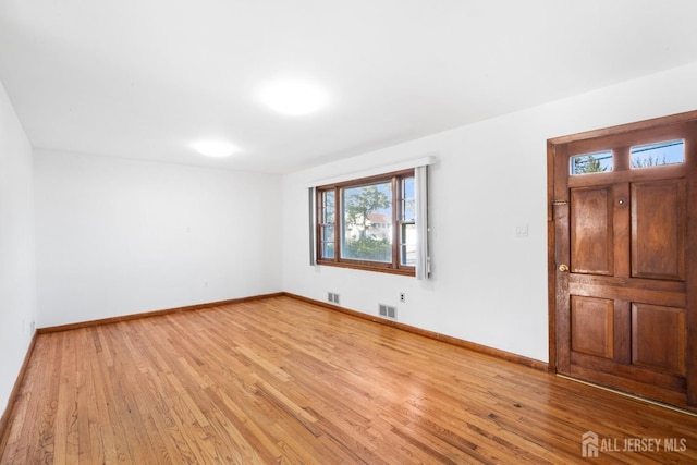 unfurnished room featuring baseboards, visible vents, and light wood-style floors