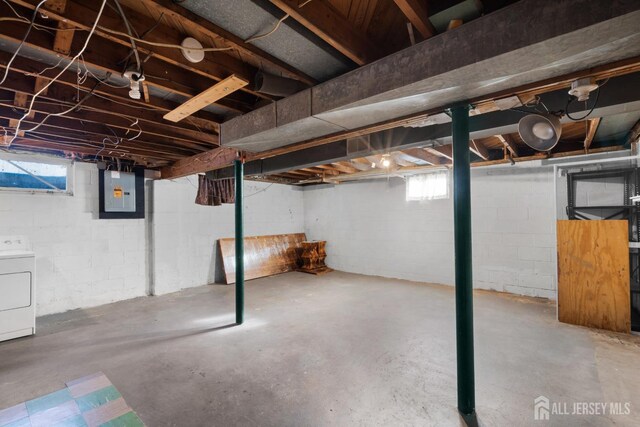 basement featuring plenty of natural light, electric panel, and washer / dryer