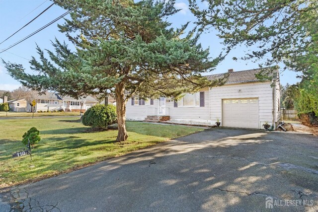 view of property hidden behind natural elements with a garage and a front lawn