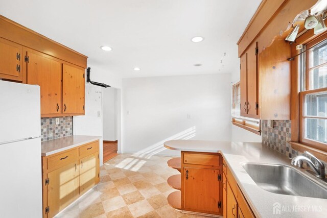 kitchen featuring sink, tasteful backsplash, kitchen peninsula, and white fridge