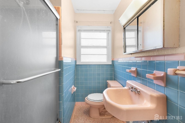 bathroom featuring sink, a shower with shower door, tile walls, and tile patterned floors