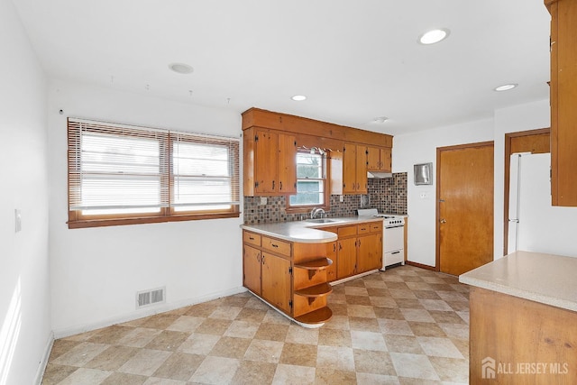 kitchen featuring white appliances, a sink, visible vents, light countertops, and tasteful backsplash