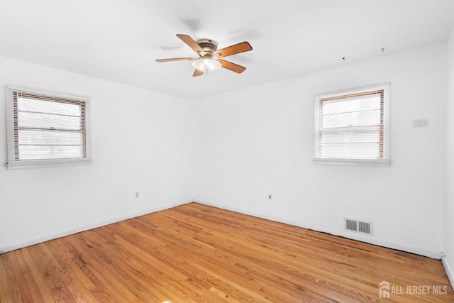 empty room with ceiling fan, light wood-style flooring, and visible vents