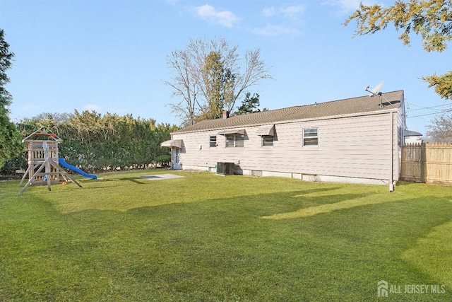 back of property featuring a playground and a yard