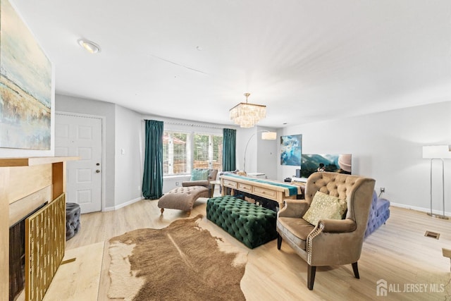 bedroom with a tiled fireplace, a chandelier, light wood-style flooring, and baseboards