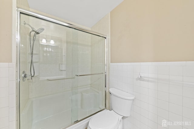 full bath featuring a shower stall, tile walls, and toilet