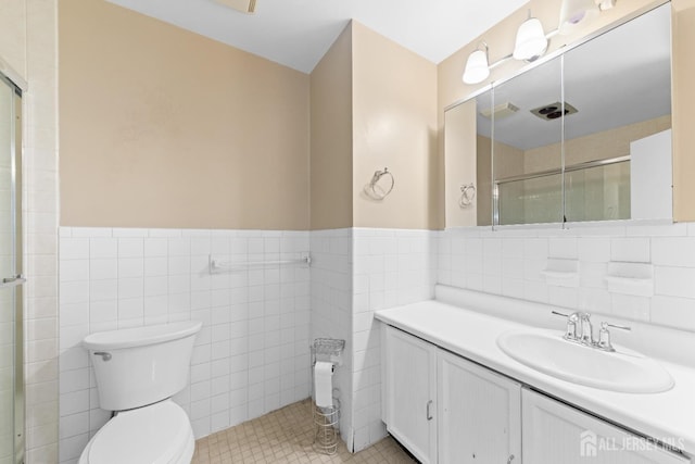 bathroom featuring a shower with door, toilet, and tile walls