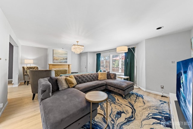 living area featuring baseboards, light wood-style floors, and a chandelier