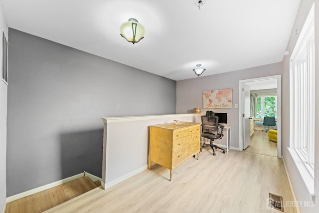 office space featuring light wood finished floors, visible vents, and baseboards