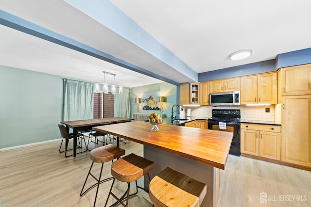 kitchen with black electric range, stainless steel microwave, tasteful backsplash, and light brown cabinets