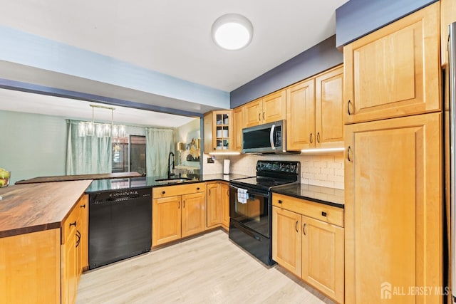 kitchen with black appliances, a peninsula, light brown cabinetry, and a sink