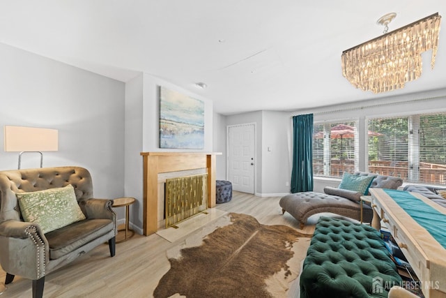 living area with a notable chandelier, a fireplace, baseboards, and light wood-style floors