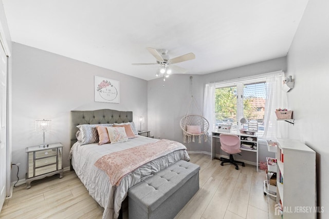 bedroom with a ceiling fan, light wood-type flooring, and baseboards