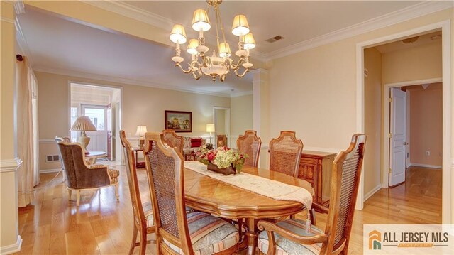 dining room featuring a notable chandelier, crown molding, light hardwood / wood-style flooring, and decorative columns