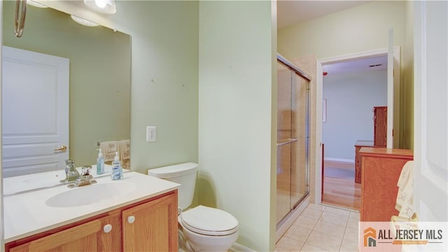 bathroom with an enclosed shower, vanity, tile patterned floors, and toilet