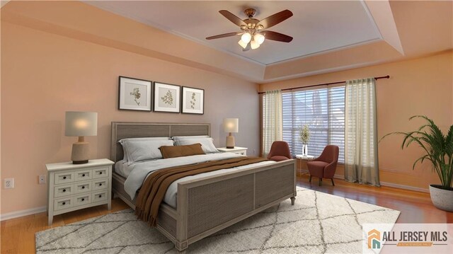 bedroom featuring light hardwood / wood-style flooring, a raised ceiling, and ceiling fan