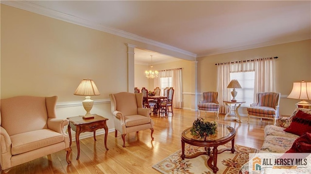 living room with ornamental molding, light hardwood / wood-style floors, a chandelier, and ornate columns