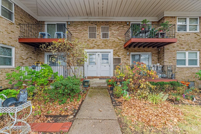 entrance to property featuring brick siding and a balcony