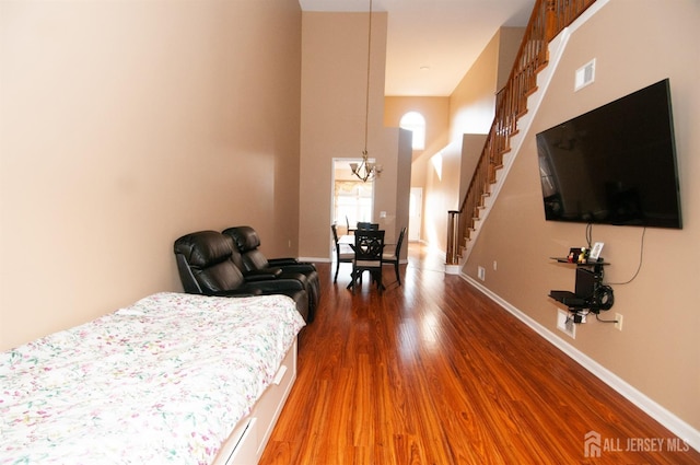 bedroom with dark hardwood / wood-style flooring, a notable chandelier, and a towering ceiling