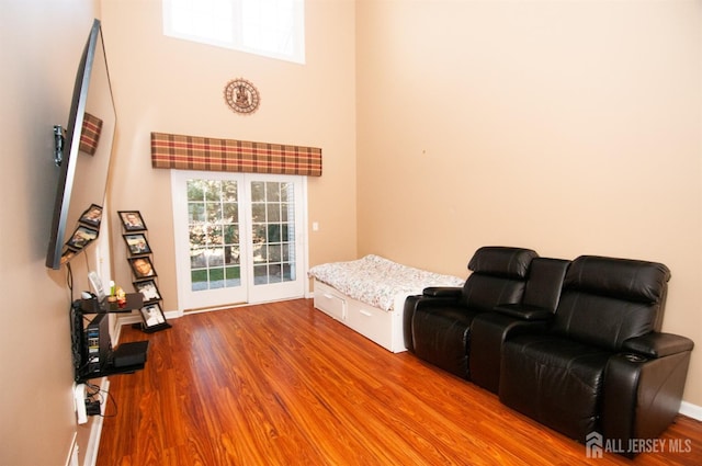 living room featuring a towering ceiling, light hardwood / wood-style flooring, and a wealth of natural light