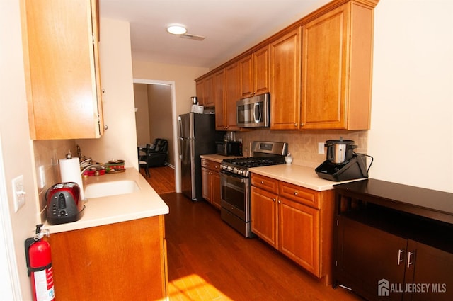 kitchen featuring sink, backsplash, stainless steel appliances, and dark hardwood / wood-style floors