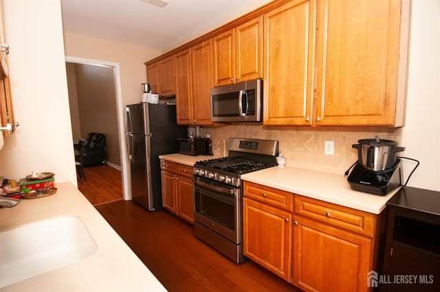 kitchen featuring appliances with stainless steel finishes, dark hardwood / wood-style flooring, sink, and decorative backsplash