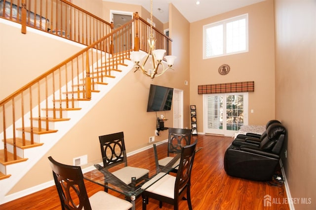 dining space featuring a high ceiling, hardwood / wood-style floors, and a notable chandelier