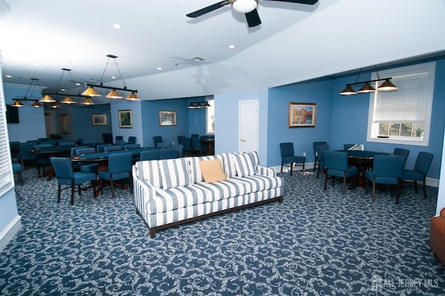 living room featuring ceiling fan and dark colored carpet