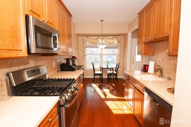 kitchen featuring sink, hanging light fixtures, appliances with stainless steel finishes, dark hardwood / wood-style flooring, and backsplash