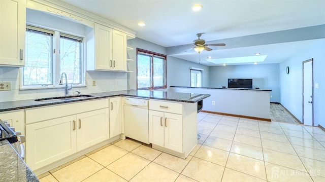 kitchen with light tile patterned floors, a sink, a ceiling fan, a peninsula, and white dishwasher