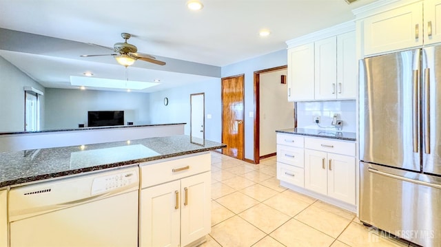 kitchen featuring dishwasher, dark stone counters, a ceiling fan, light tile patterned floors, and freestanding refrigerator