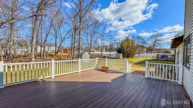 deck featuring a storage shed, fence, a lawn, and an outdoor structure