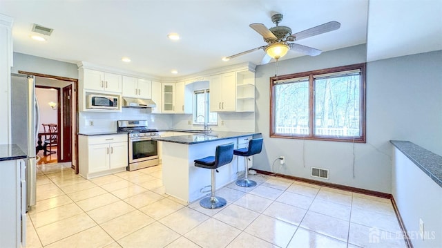 kitchen with a kitchen breakfast bar, stainless steel appliances, visible vents, and under cabinet range hood