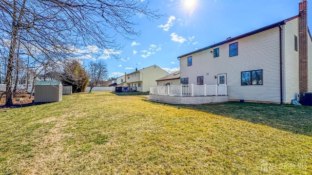 back of property featuring a wooden deck, an outbuilding, a yard, and a storage shed
