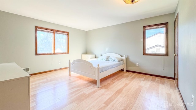 bedroom with light wood finished floors, baseboards, and visible vents