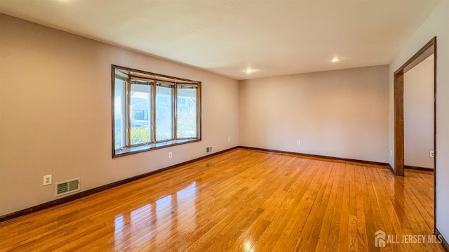 unfurnished room featuring visible vents, light wood-style flooring, and baseboards